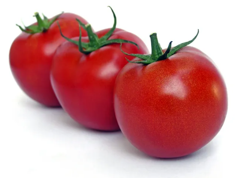Three tomatoes are lined up on a white surface.